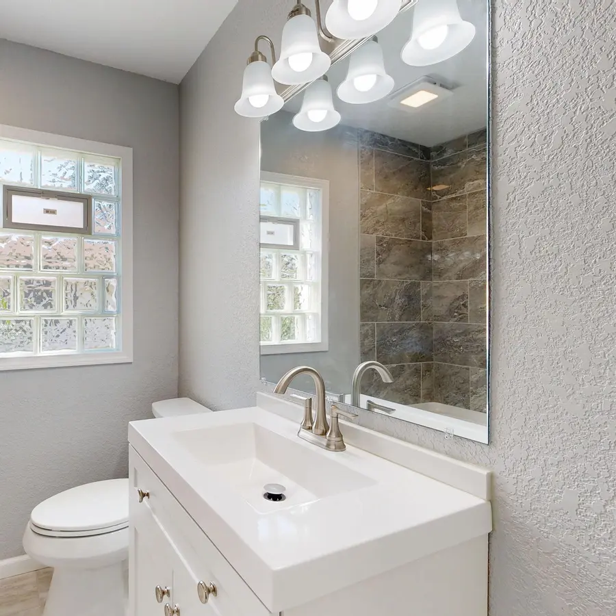 Remodeled bathroom with a white vanity, gray tile and a window