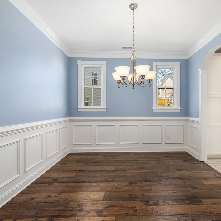 Blue dining room with white wainscoting, crown molding and a chandelier