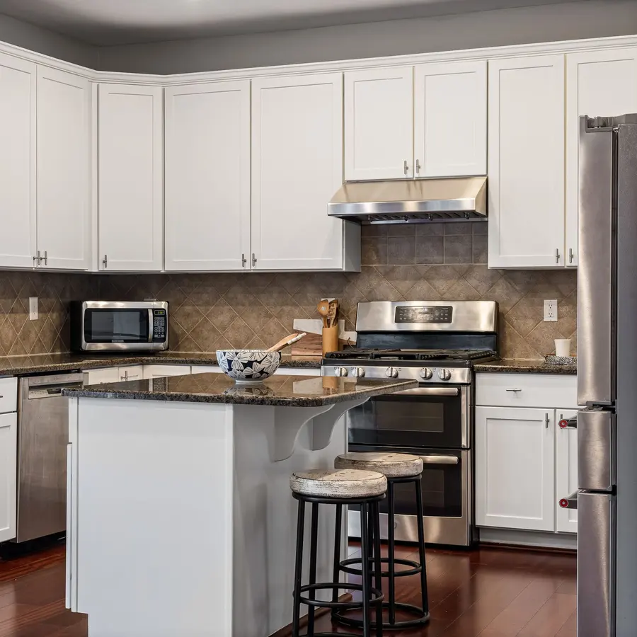 White kitchen with an island, granite countertops and bar stools