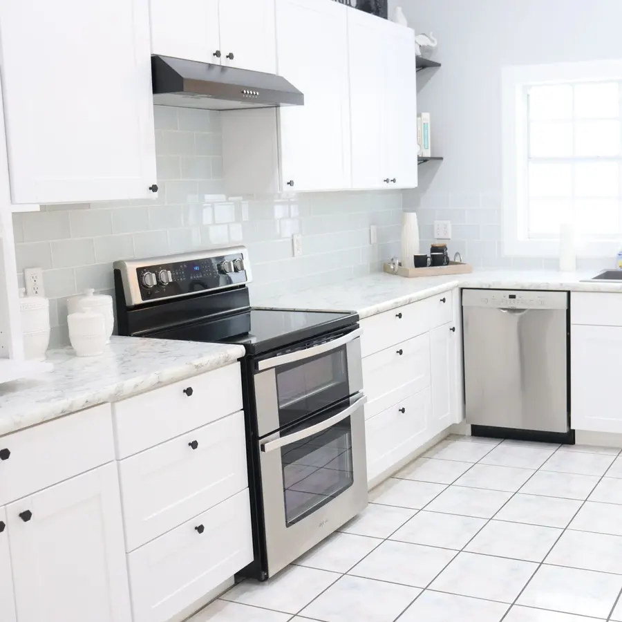 U-shaped white kitchen with stainless steel appliances and tile floor