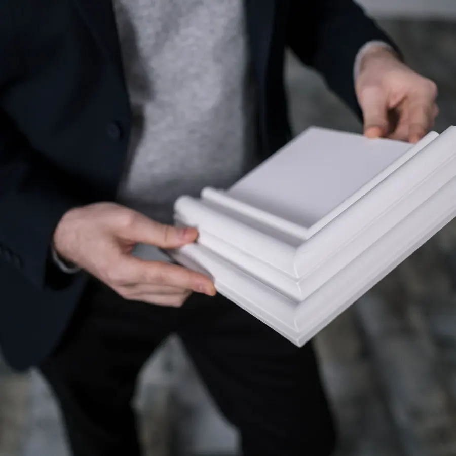 Hands holding white crown molding samples