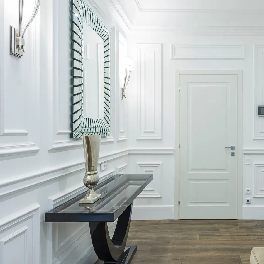 White room with classic wall paneling, a mirror and a console table