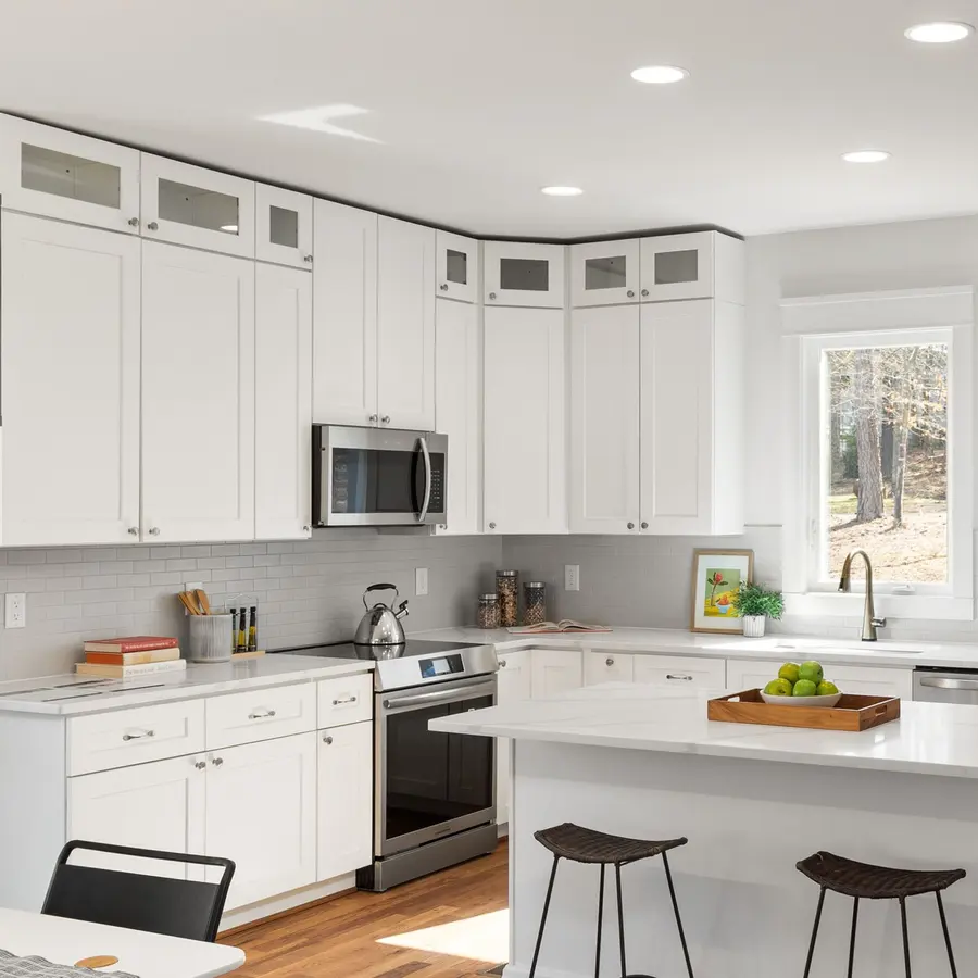 Bright white kitchen with an island, tall cabinets and wood floors