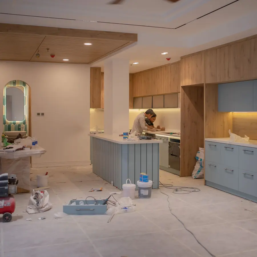 Kitchen remodel in progress with new cabinets, an island and a worker finishing details